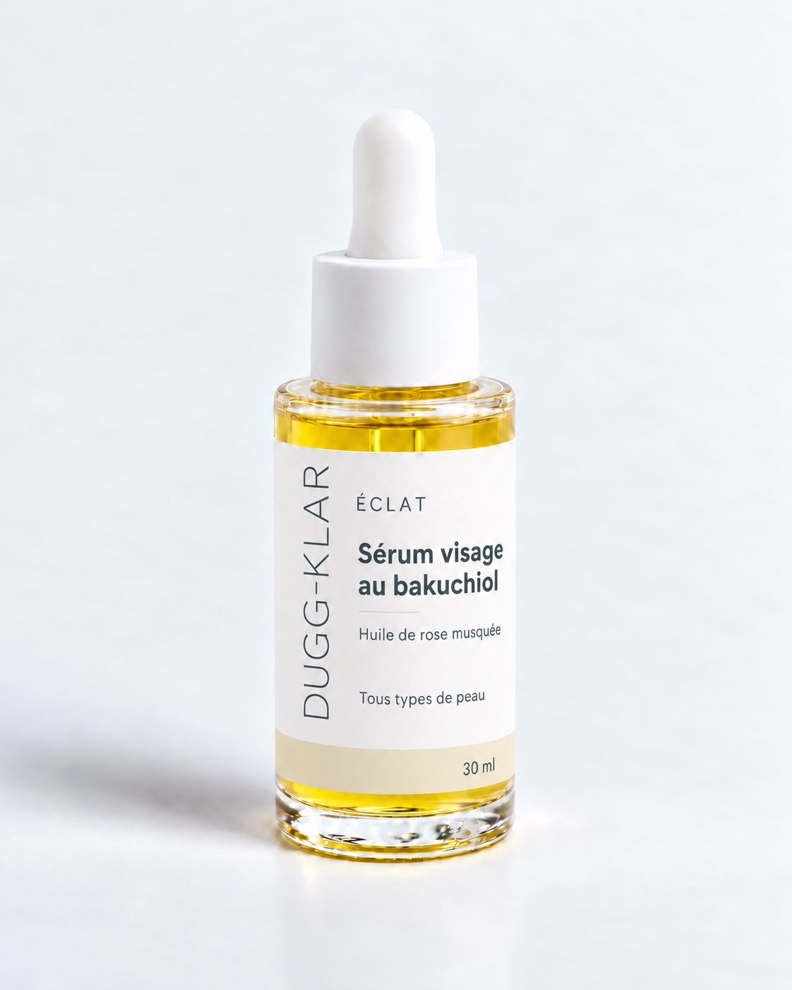 DUGG-KLAR Éclat, sérum visage au bakuchiol 30 ml, flacon transparent à pipette blanche, étiquette au logo vertical fin gris ardoise et bande champagne.